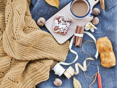 A blanket, a cup of tea some leaves and spices on blue picnic blanket