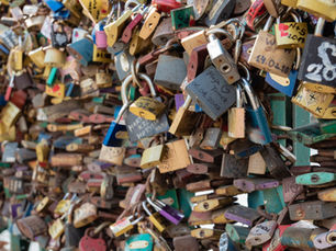 Colorful padlocks crowded on a bridge railing, many with names and dates written on them, creating a dense, romantic display.