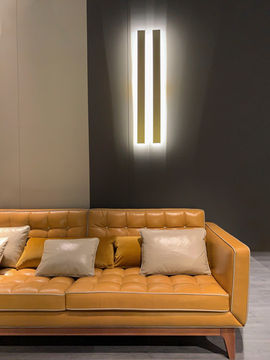 moderne senffarbene Couch, zwei Lampen an der Wand