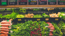 Pasillo de productos frescos de un supermercado donde se venden zanahorias, cilantro, espinacas y lechuga.