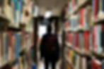 Student walking down library aisle