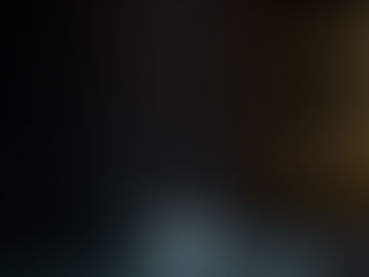 White pills scattered on a dark surface beside a blurred medicine bottle in low, moody light.