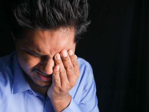 Stressed man rubbing his eye from eye strain, headache, or fatigue while working | South Bay Retina, Gilroy, San Jose