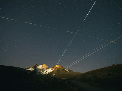 Long exposure night sky with light trails over a mountain, representing nationwide virtual grief support, community connection, and online therapy access across the U.S.