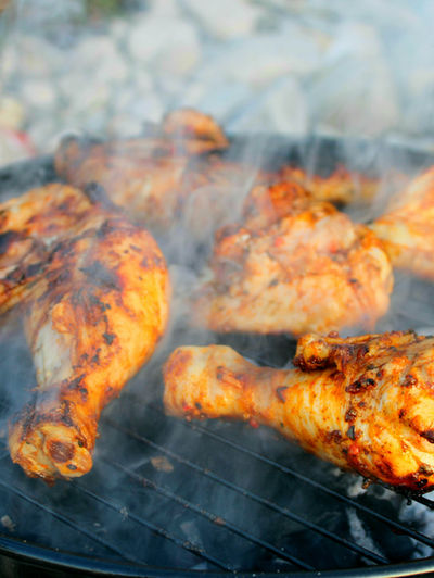 BBQ chicken seasoned with Fowl Play dry rub grilling over flames with crispy charred skin and smoky golden colour