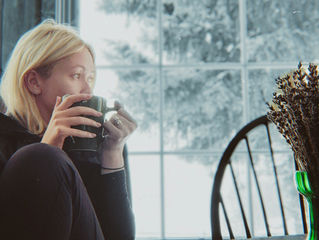 A woman sitting quietly with a cup of tea at dawn while the rest of the house sleeps.