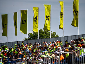 Lando Norris branded flags blowing in the wind above a grandstand.