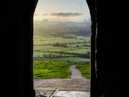 A rustic stone doorway opening to a misty view of the Scottish Highlands, symbolizing entry into a past life journey and self-discovery.