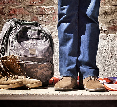 Image by Benjamin Faust of man standing in jeans next to a military camouflage backpack and boots