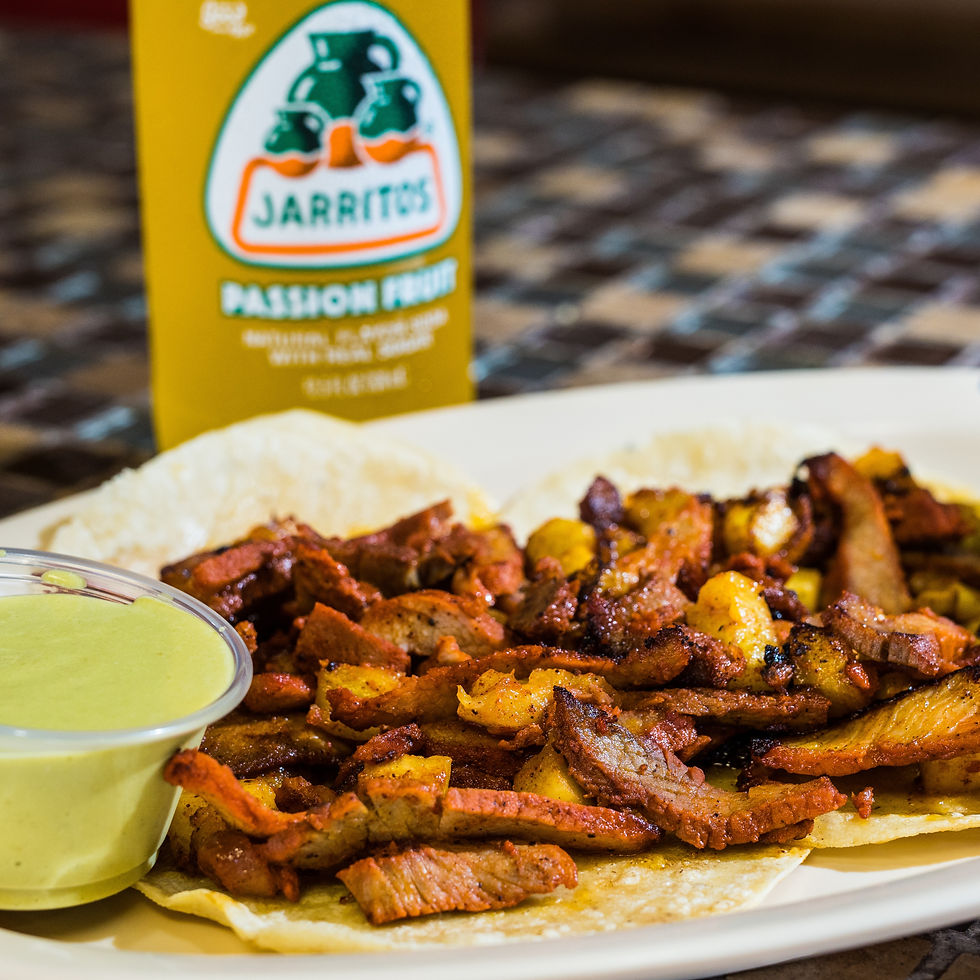 Close-up view of a plate with tacos al pastor, garnished with pineapple and cilantro