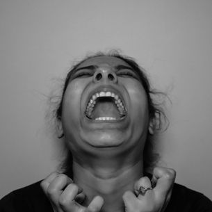Black and white image of a distressed person screaming with fists clenched, illustrating frustration and anger related to the consequences of making threats under Louisiana law.