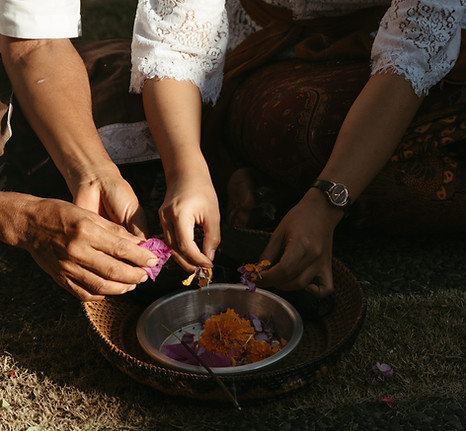 Women placing flowers in a ceremonial bowl