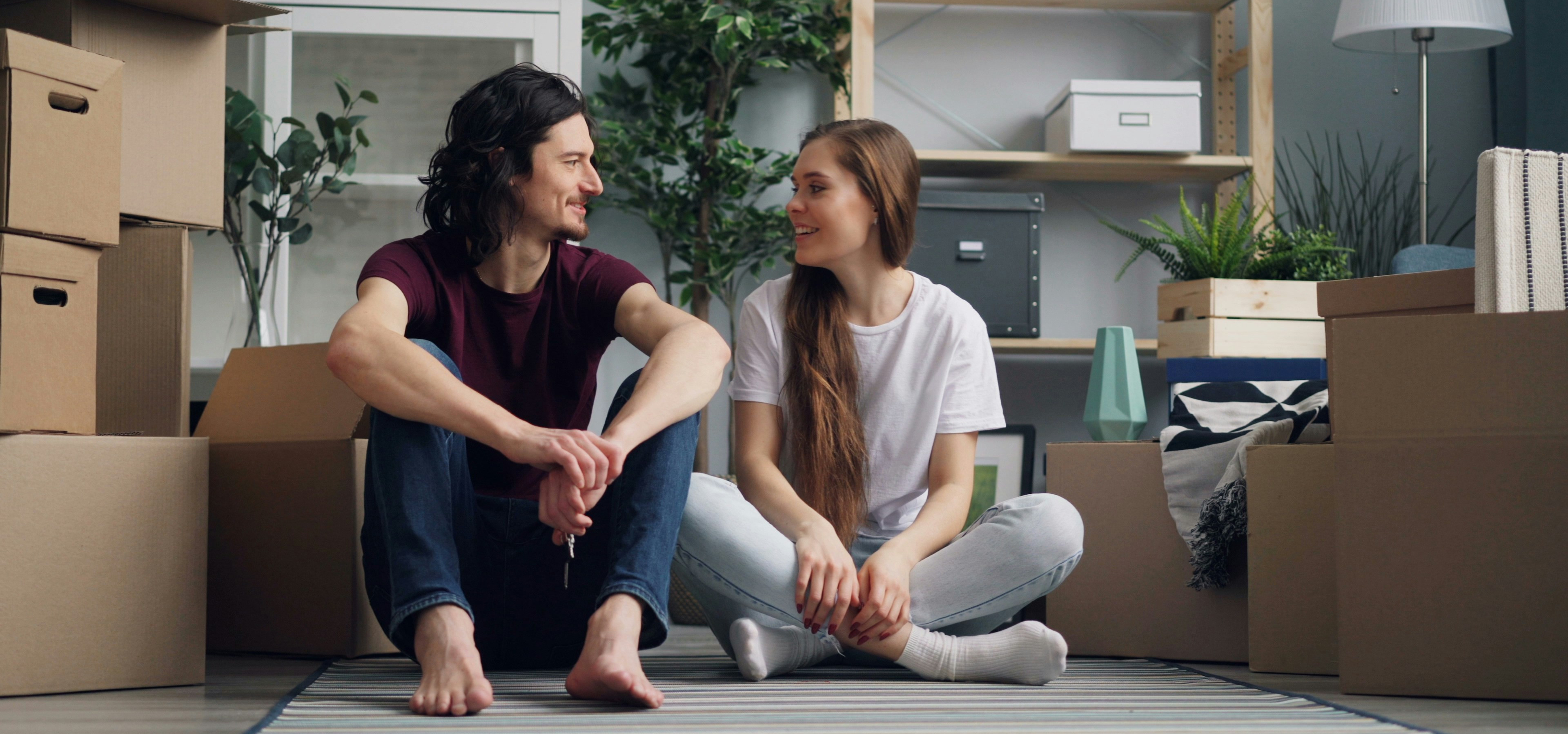 A couple sits around moving boxes
