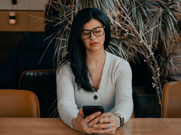woman is seated and scrolling on her smartphone