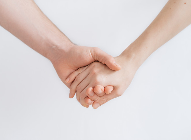 Two hands gently holding each other, symbolizing care, support, and human connection.