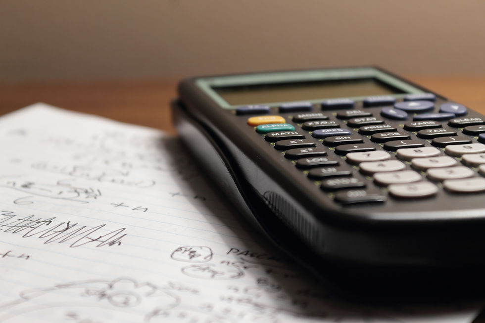 Gambar close-up sebuah kalkulator ilmiah hitam yang diletakkan di atas lembaran kertas dengan tulisan dan perhitungan matematika tangan. Kalkulator memiliki tombol-tombol berwarna berbeda untuk fungsi matematika.