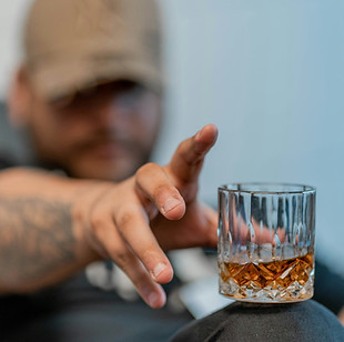 Image by Rodrigo Rodrigues of man reaching for a glass of alcohol