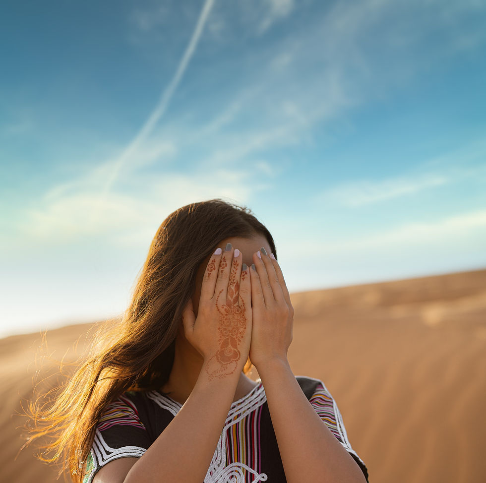 A woman in nature covering her face so as not to see