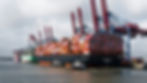 Large container ships docked at a busy port terminal with cargo cranes, illustrating global port congestion in 2026.