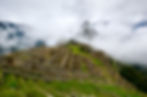Machu Picchu emerges mystically through the fog, its age-old ruins encircled by drifting clouds.