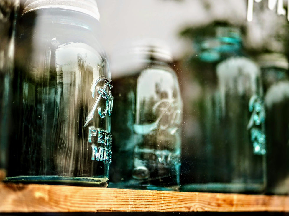 Empty canning jars line a wooden shelf, ready to be filled with homemade jams and spreads.