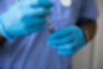 Hands in blue medical gloves preparing a syringe from a vial.