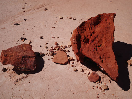 Deux blocs d’argile rouge posés sur un sol sec et craquelé, sous la lumière du sud tunisien.