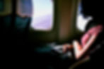 woman looks out the window of an airplane. it's bright outside but dark in the cabin