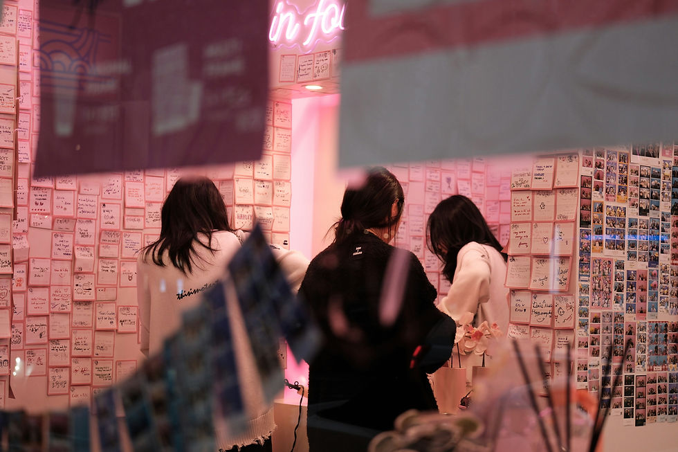3 women shopping in pink walled and lit area.