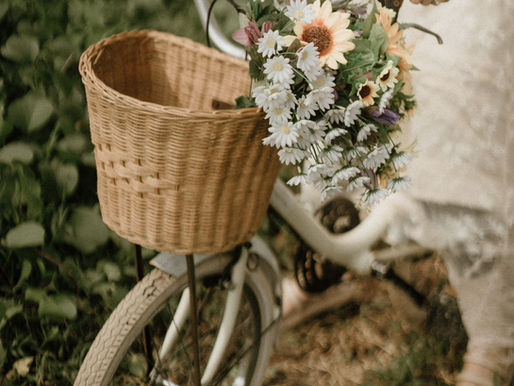 the front of a bicycle with a basket on the front and some flowers