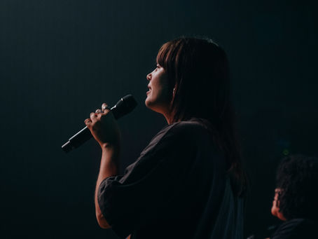 Female Worship Leader leading worship on stage during live worship service.