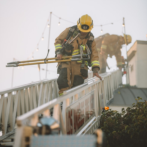 Two firefighters in full gear ascend a ladder