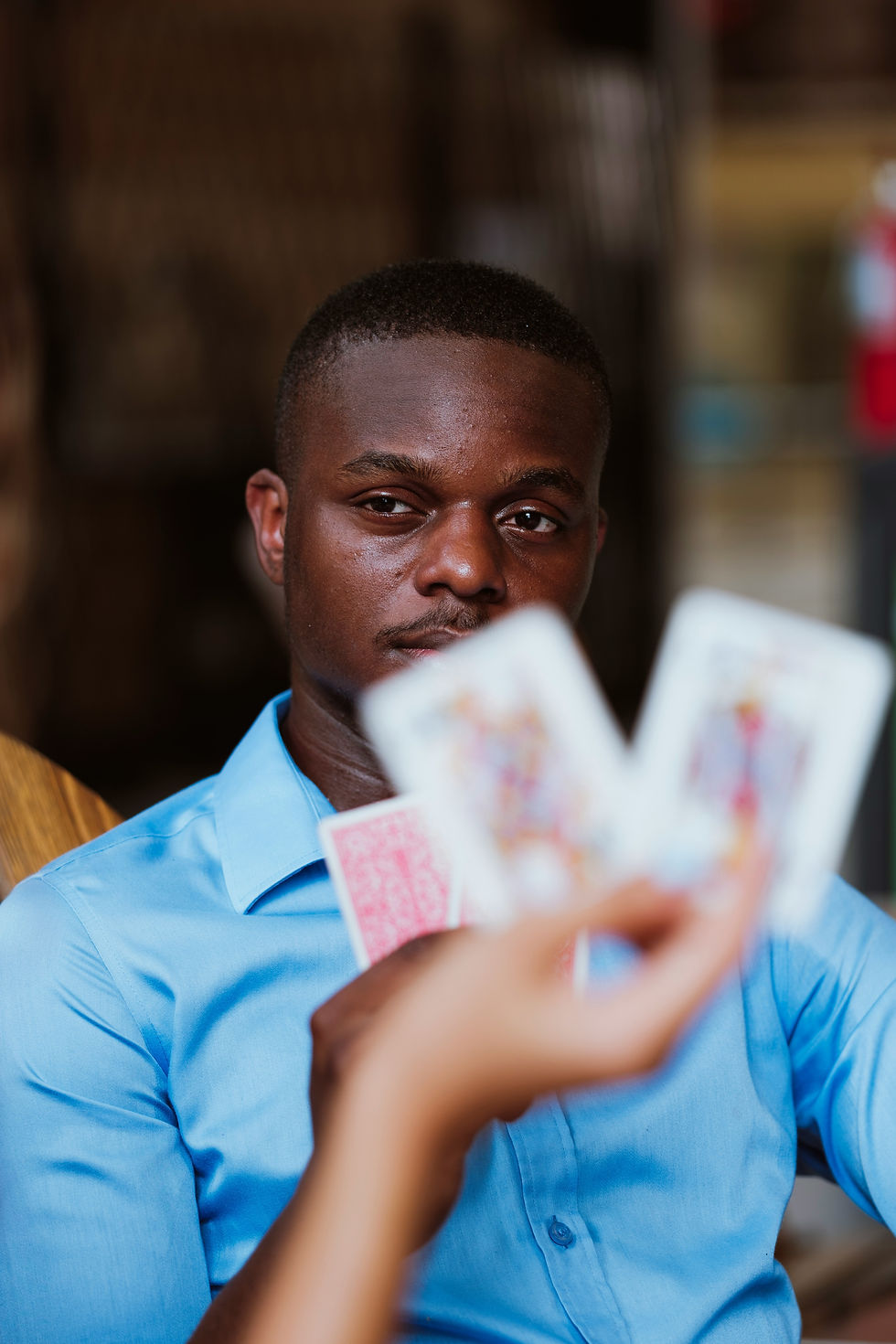 a person staring at the camera while the other person holds up a poker hand