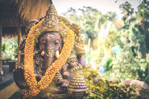 Ganesha Statue vor verschwommenem Hintergrund, der an eine Balinesische Unterkunft erinnert.