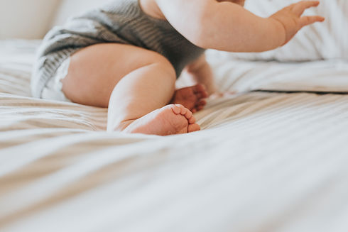 Baby in sage onesie on the bed