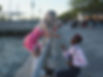 Girl in pink dress leaning over railings while another girl proposes to her.