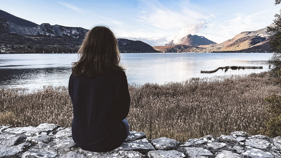 woman sitting and looking out at a lake