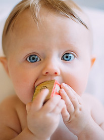 Kleines Kind mit Spielzeug im Mund