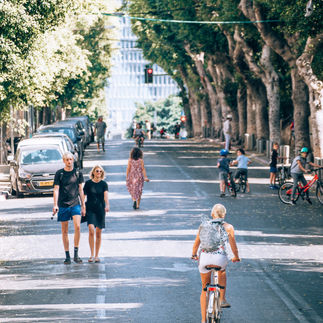 Pedestrians and cyclists enjoying a tree-lined boulevard on Rothschild Boulevard.