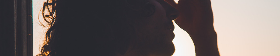 Person sitting with head bowed near a window, representing stress and emotional overwhelm