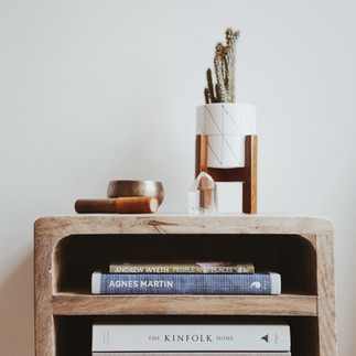 A wooden bedside table with books and a green plant on top create a warm atmosphere, adding a natural touch to the bedroom.
