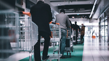 A line of people pushing shopping baskets