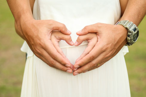 Couple forming a heart shape with their hands during their maternity photography session in a New York park.