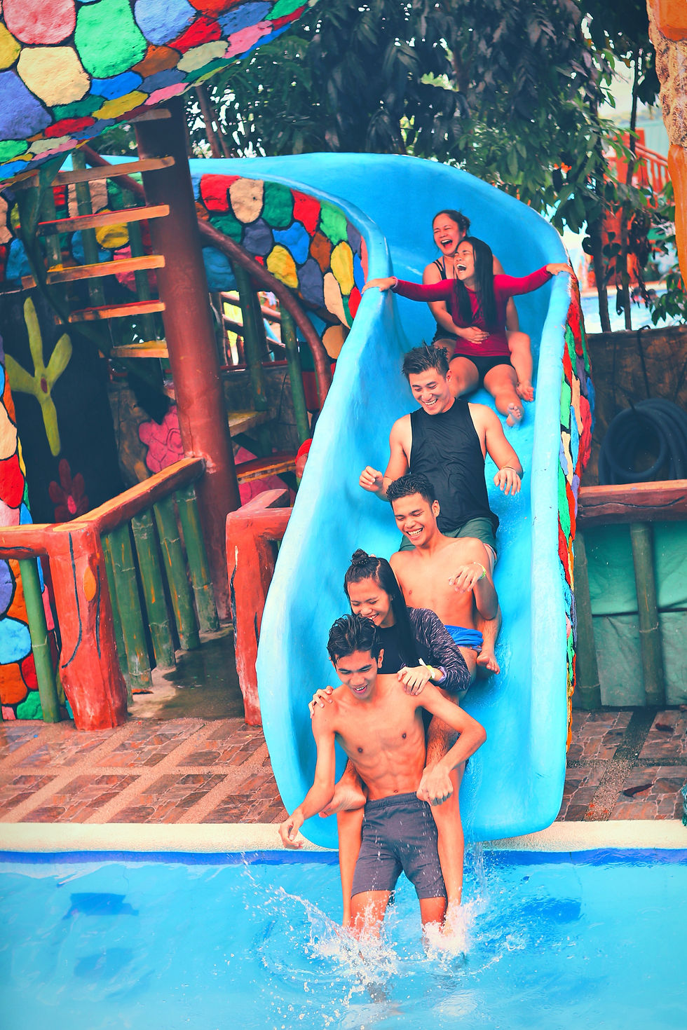 6 people sliding down a water slide into a pool