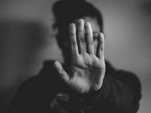 "Black and white image of a person holding up a hand to block or deflect, symbolising uncertainty or resistance."