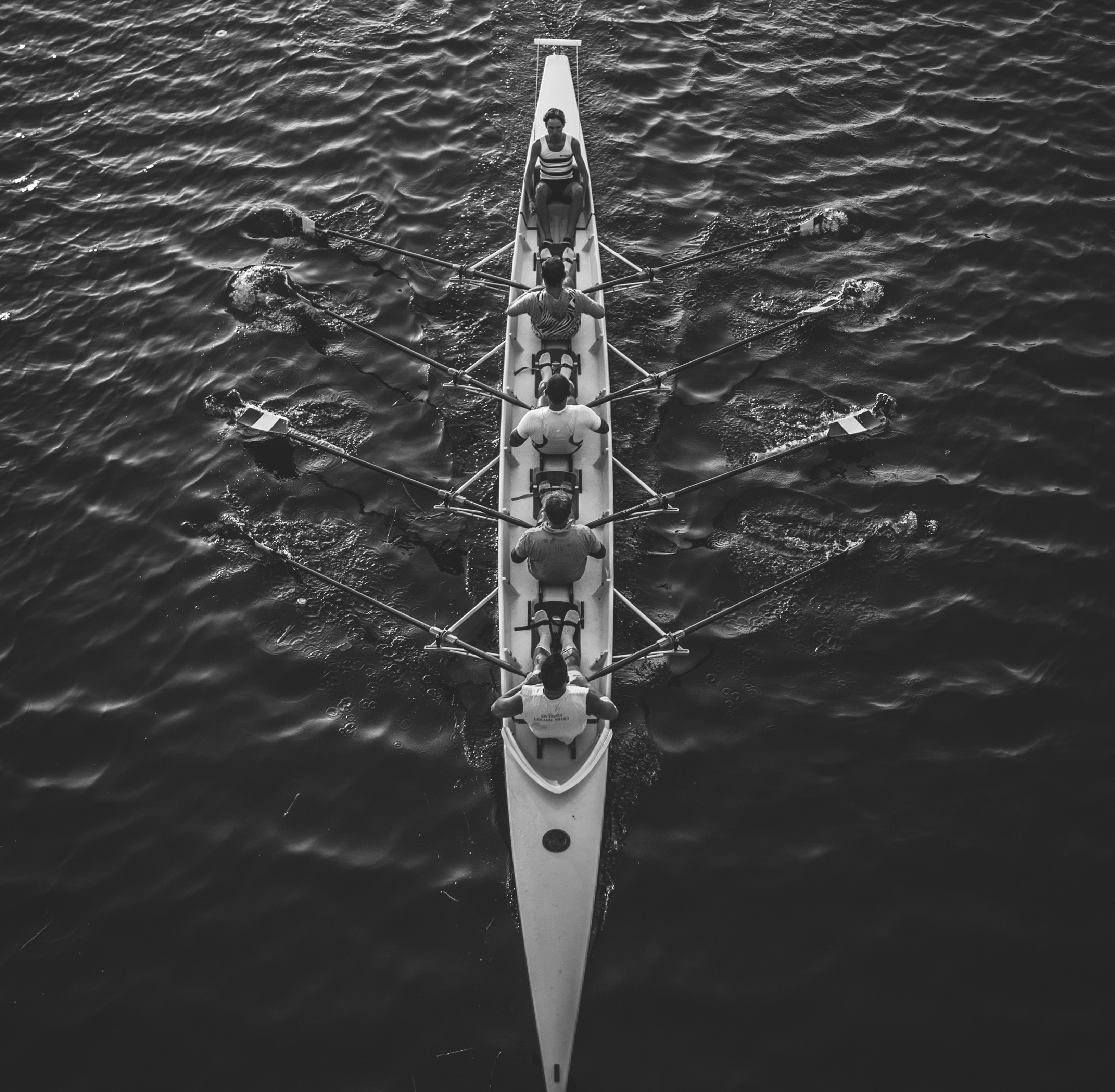 photo en noir et blanc un averon sur l'eau quatre rameur et le leader en tete
