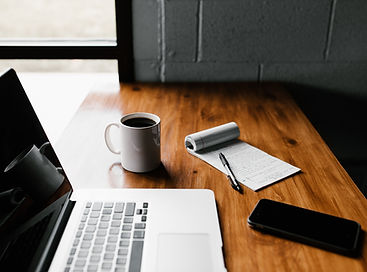 Coffee on table with notepad, computer, and phone