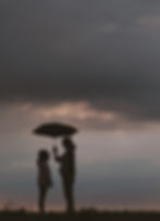 A woman standing next to her daughter holding an umbrella.