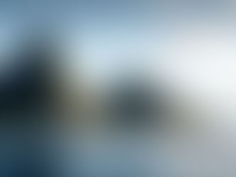 Bateau blanc naviguant devant deux montagnes verdoyantes sous un ciel bleu avec quelques nuages. Mer calme reflétant une atmosphère sereine.