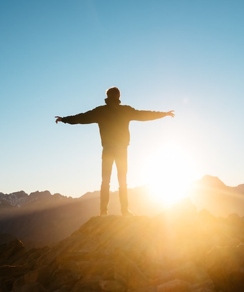 Man on top of a hill or mountain looking at blue sky | Image by Pablo Heimplatz